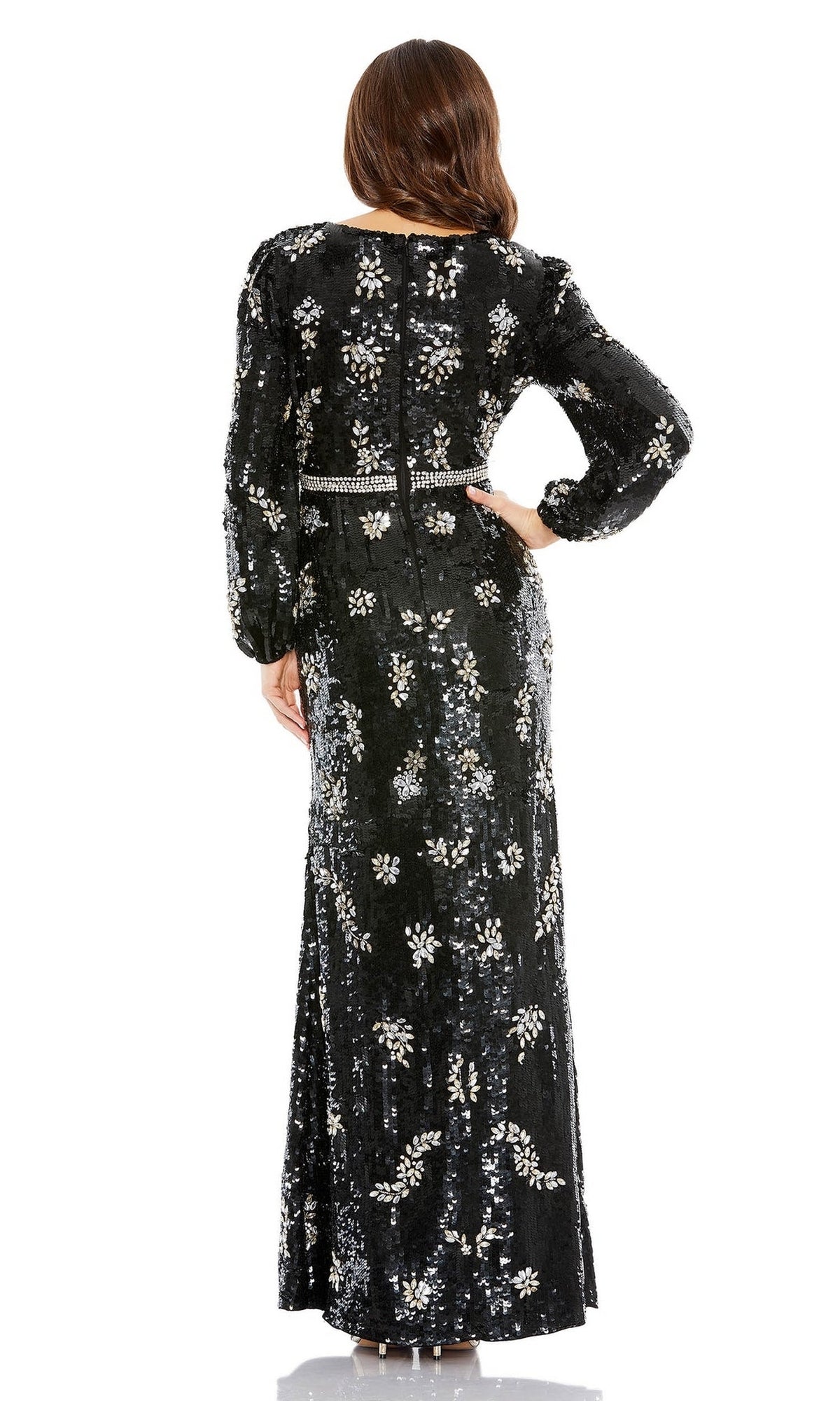 A woman stands facing away, wearing the Long Formal Dress 93616 by Mac Duggal—a black sequin evening gown with silver embellishments and long sleeves.